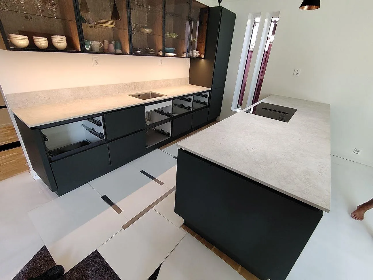 Matt köksbänkskiva i Dekton Tk05 Sabbia med köksö, låg stänkkant och mörka köksstommar under montering i Falun.