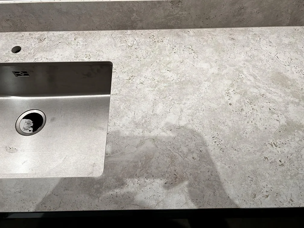 Närbild av matt Dekton Tk05 Sabbia med rostfri diskho, blandarhål och ljus betonglik struktur i Göteborg.