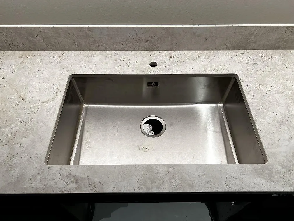 Underlimmad rostfri diskho i köksbänkskiva av matt Dekton Tk05 Sabbia med uppvikt stänkskydd i Göteborg.