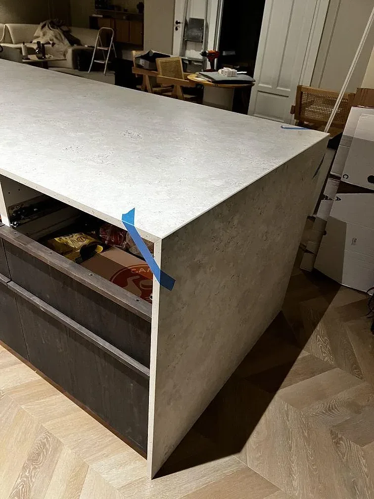 Köksö med topp i matt Dekton Tk05 Sabbia och sidostycke under montering i Göteborg.