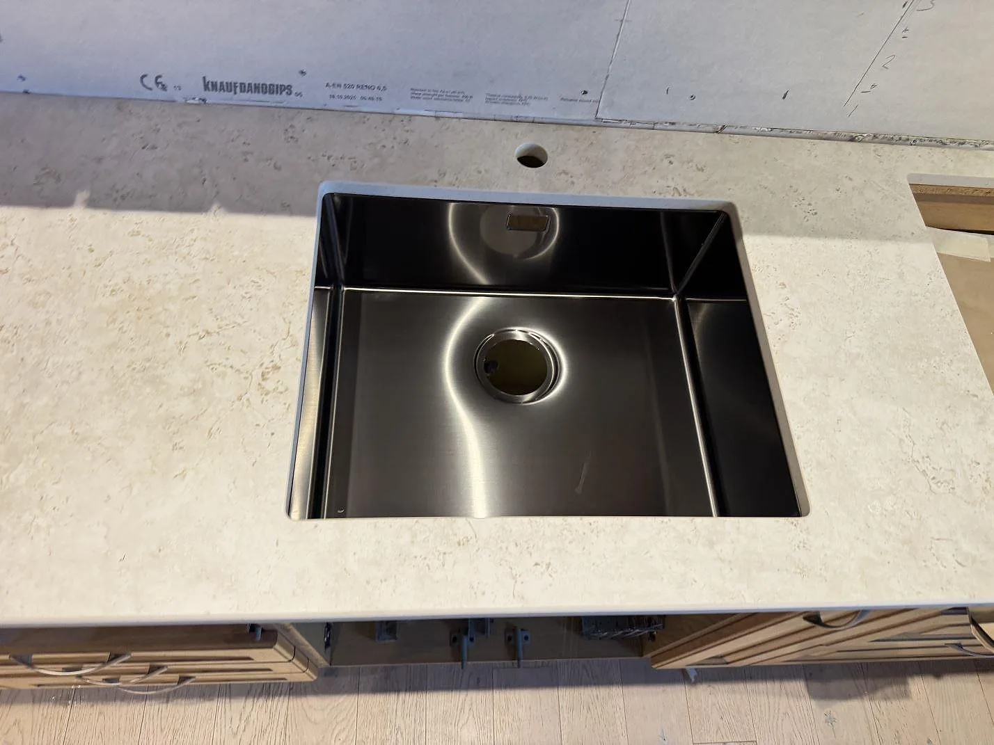 Underlimmad rostfri diskho i köksbänkskiva av Dekton TK05 Sabbia i Hasslö, sett ovanifrån med matt kalkstenston.