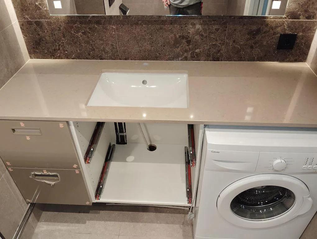 Tvättställsskiva i matt Dekton Tk05 Sabbia, 20 mm, med vitt tvättställ och tvättmaskin i ett badrum i Järfälla.