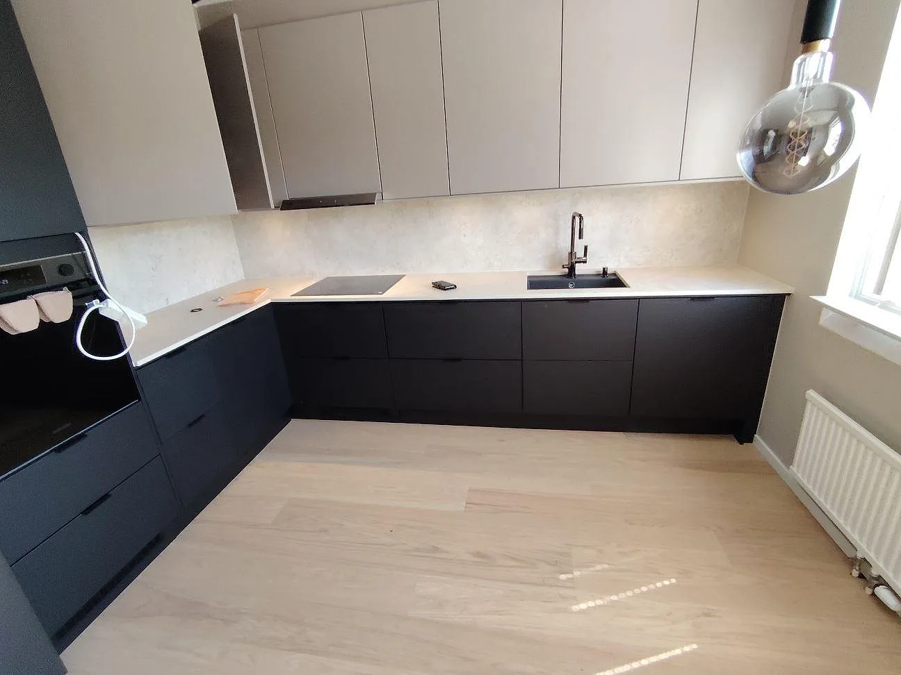Köksbänkskiva i matt Dekton Tk05 Sabbia med underlimmad diskho och häll i ett U-format kök i Järfälla.