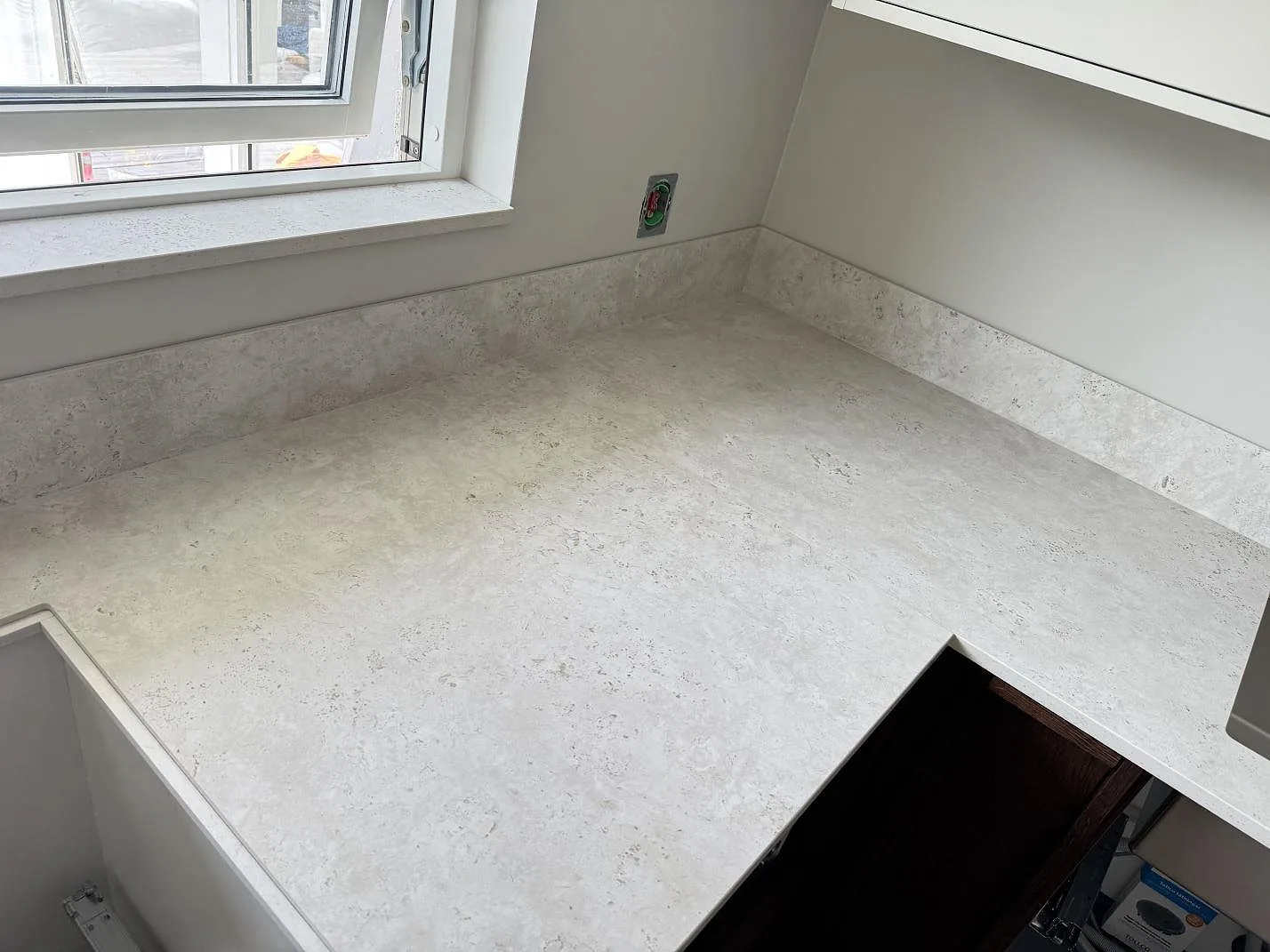 L-formad bänkskiva i matt Dekton Tk05 Sabbia med stänkskydd vid fönster och hällöppning i Lindome.
