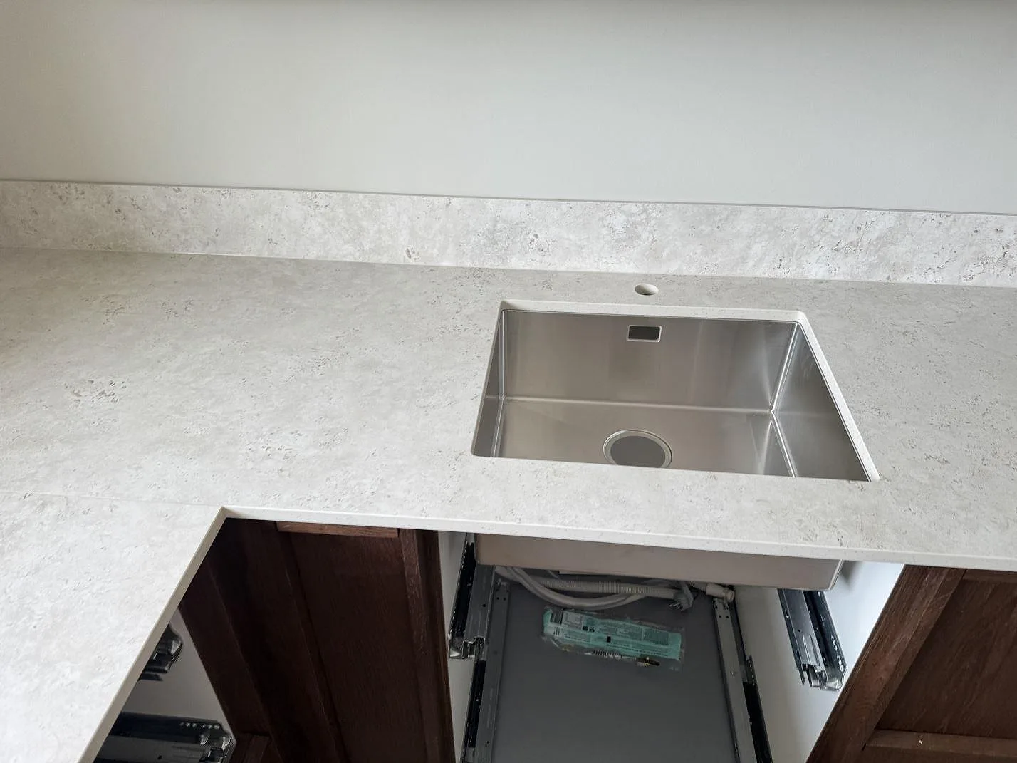 Köksbänkskiva i matt Dekton Tk05 Sabbia med rostfri diskho och öppna lådstommar i ett kök i Lindome.