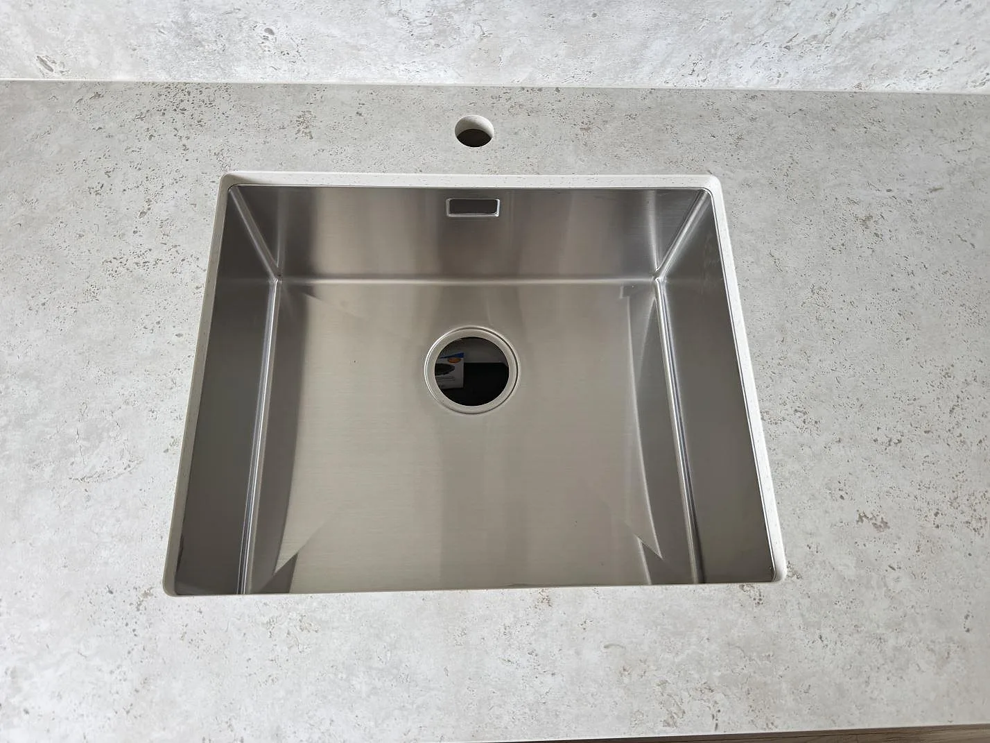 Närbild på rostfri diskho i matt Dekton Tk05 Sabbia med blandarhål och 8 mm stänkskydd i Lindome.