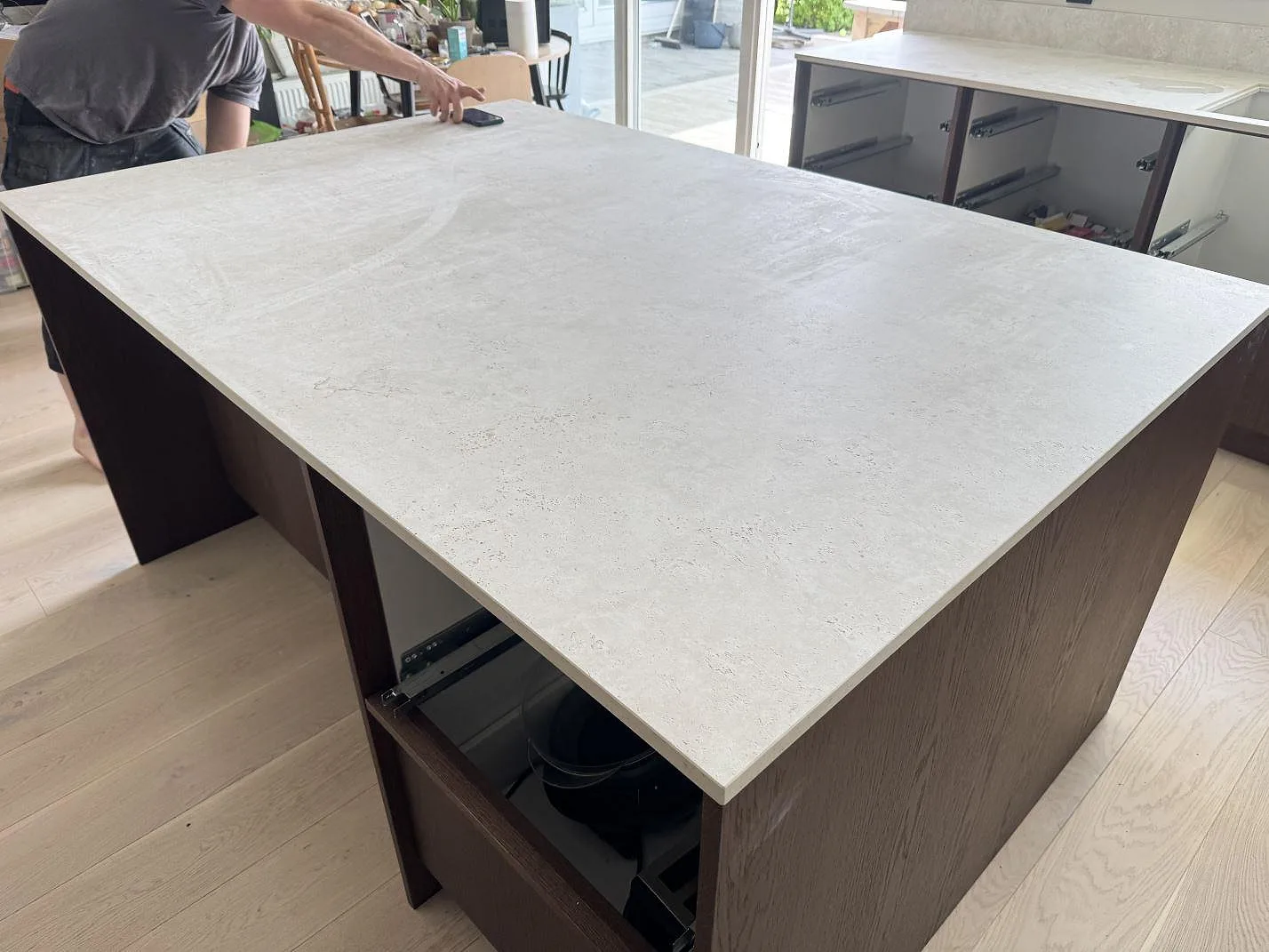 Stor köksö med matt Dekton Tk05 Sabbia och ljus stenstruktur under montering i ett kök i Lindome.