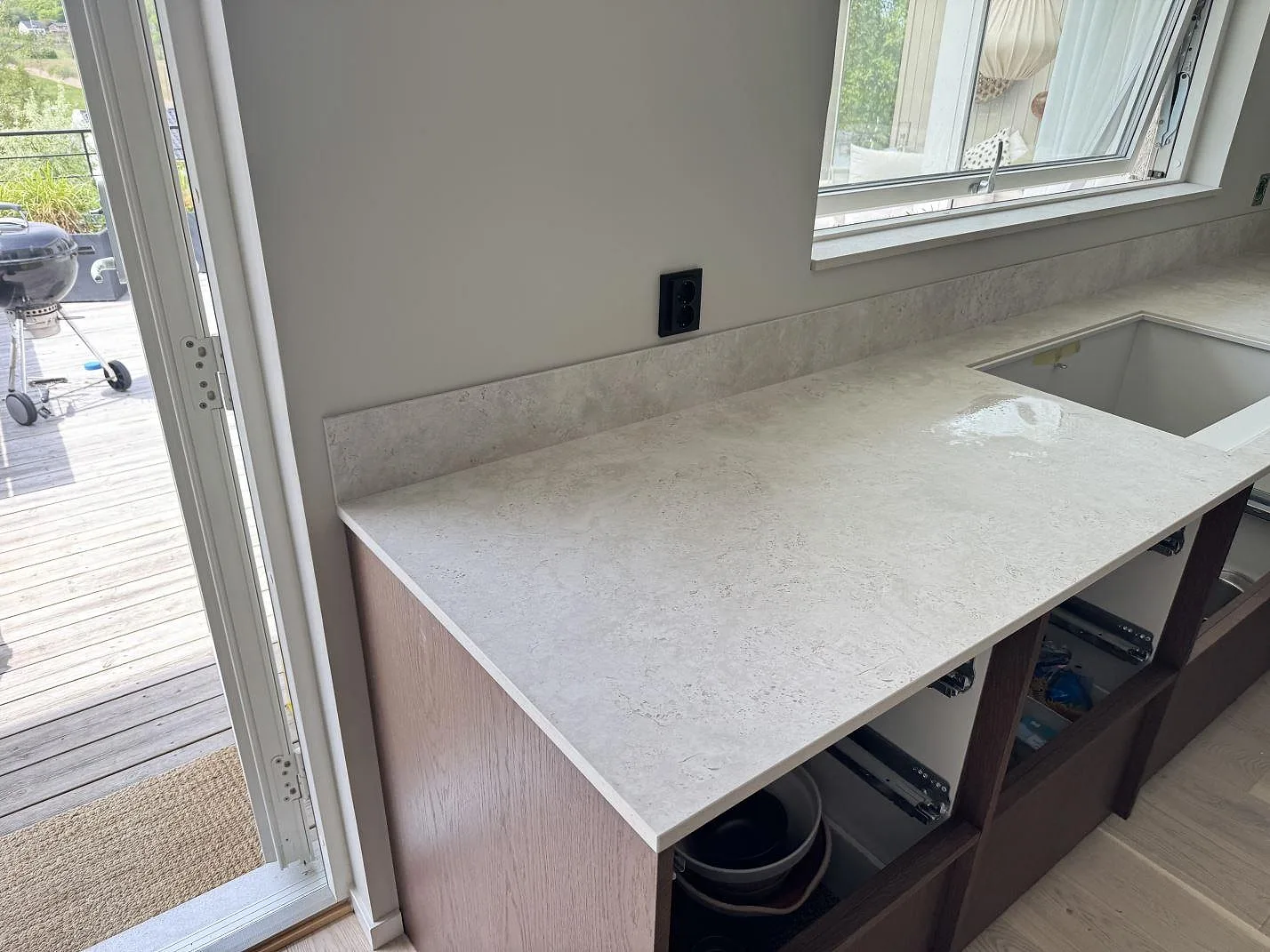 Matt köksbänkskiva i Dekton Tk05 Sabbia med uppvikt stänkskydd, fönsterläge och öppen köksstomme i Lindome.