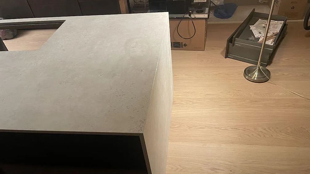 Hörnvy över köksö i matt Dekton Tk05 Sabbia med vattenfallsida och hälluttag i Lomma.