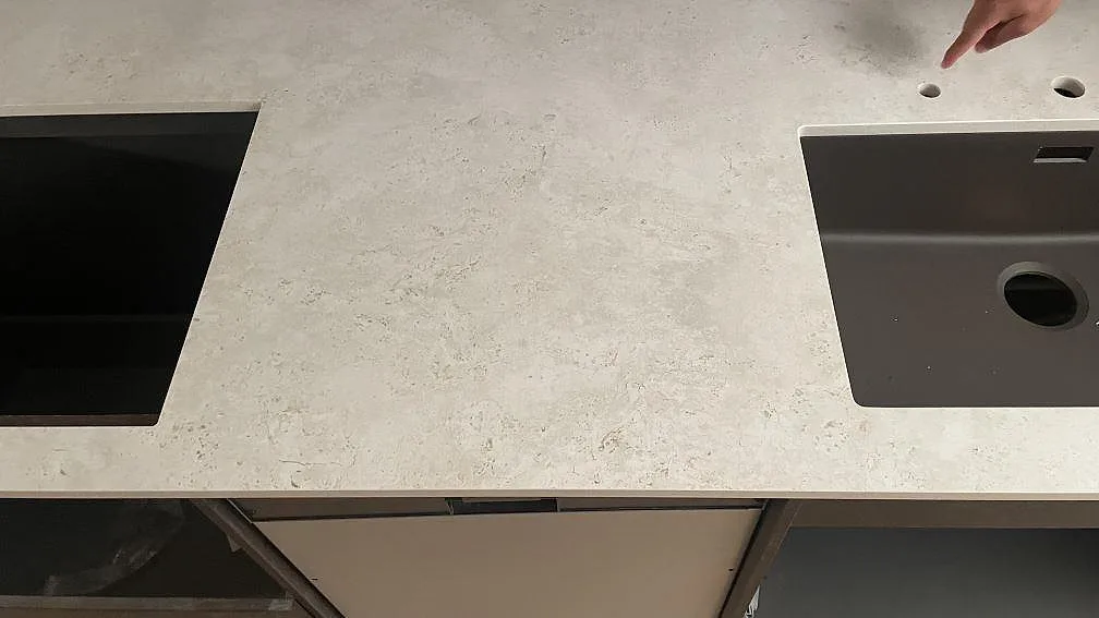 Närbild av matt Dekton Tk05 Sabbia med hälluttag, mörk diskho och blandarhål i köket i Lomma.