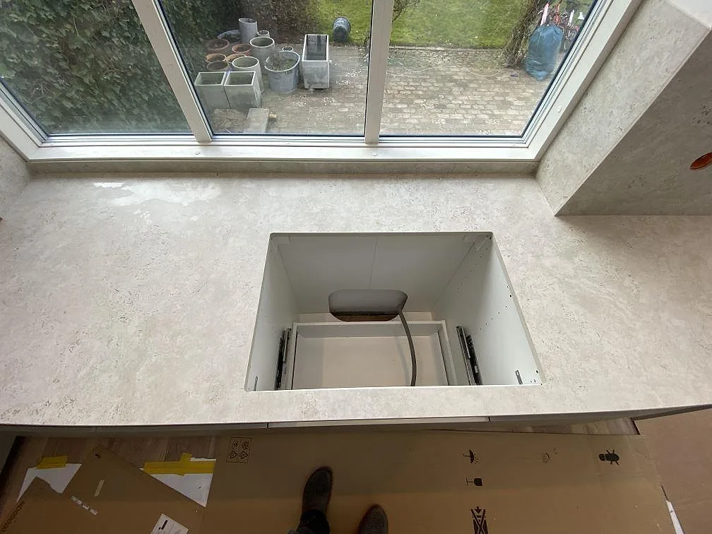 Matt köksbänkskiva i Dekton Tk05 Sabbia under fönster med rektangulärt urtag och 8 mm stänkskydd i Malmö.