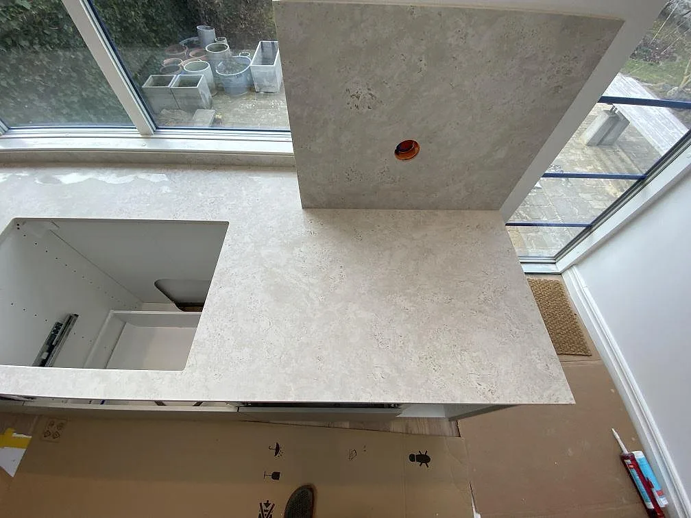 Arbetsyta i matt Dekton Tk05 Sabbia med sidostänkskydd, ljus keramisk struktur och öppna stommar i Malmö.