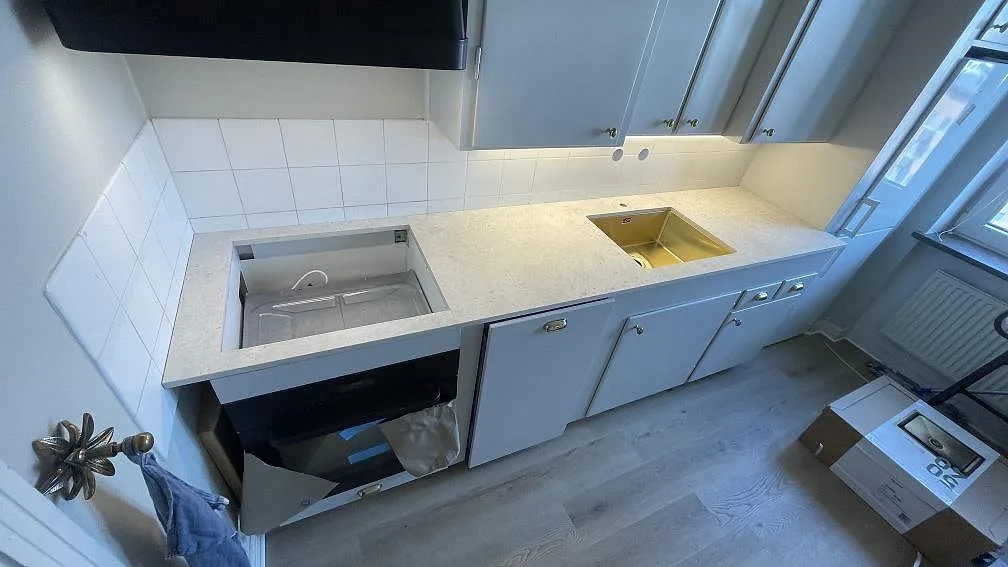 Köksbänkskiva i matt Dekton Tk05 Sabbia, 20 mm, med diskho och hällöppning i ett kök i Malmö.