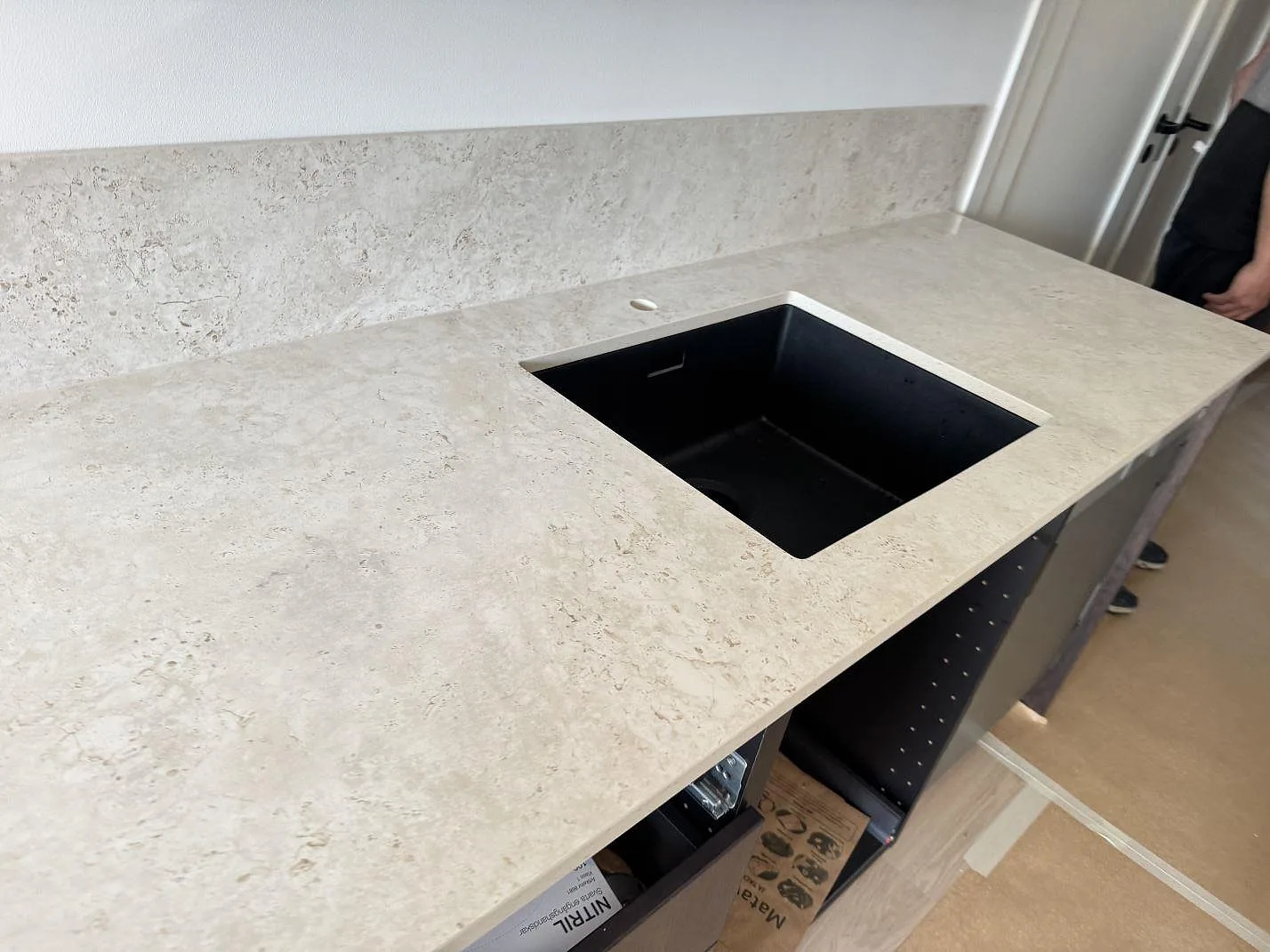 Köksbänkskiva i matt Dekton Tk05 Sabbia, keramik, med svart underlimmad diskho och blandarhål i ett kök i Malmö.