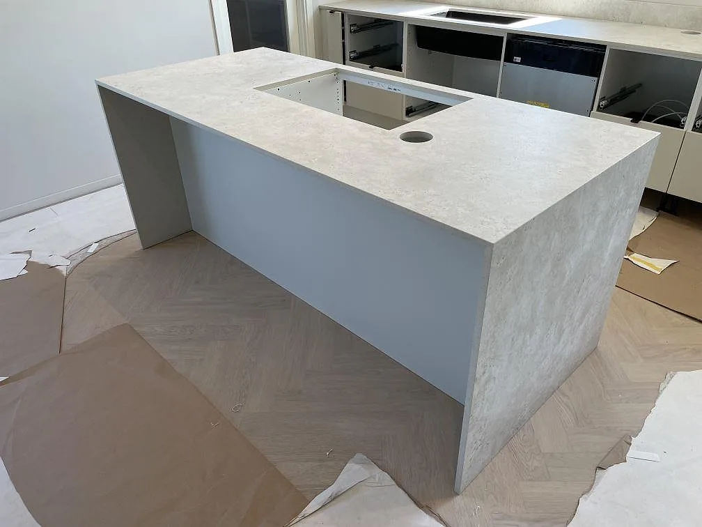 Matt Dekton Tk05 Sabbia på köksö i Örebro, med hällurtag, rund öppning och ljus keramikyta över skyddad parkett.