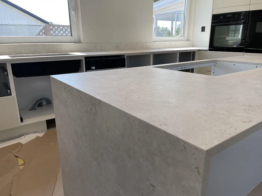 Närbild på köksö och bänkskiva i matt Dekton Tk05 Sabbia, där keramikens sandbeige mönster och stänkskydd syns i Örebro.