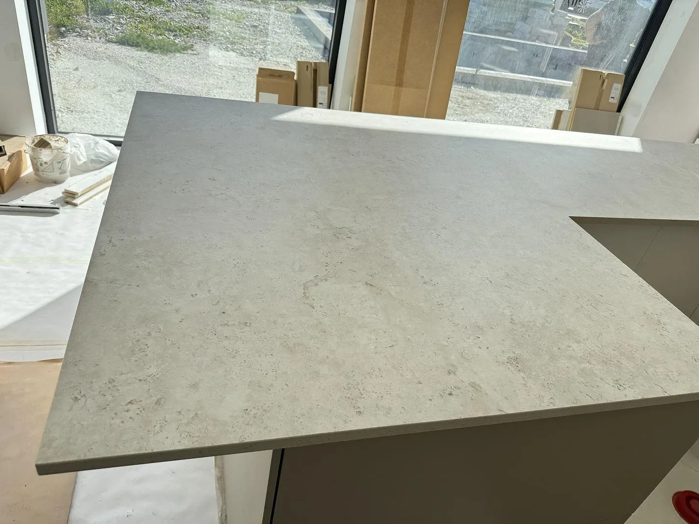 Närbild på köksö i matt Dekton Tk05 Sabbia med sandgrå keramisk yta och dagsljus i Oxie.