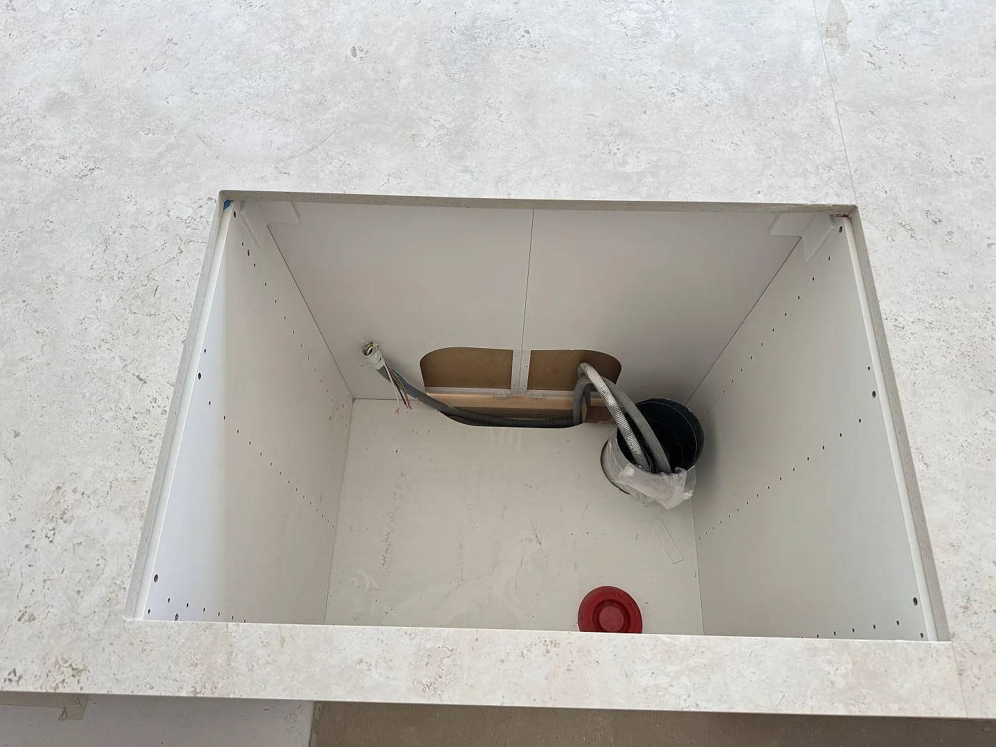 Diskhoöppning i matt Dekton Tk05 Sabbia ovanför köksstomme med installationer synliga i Oxie.