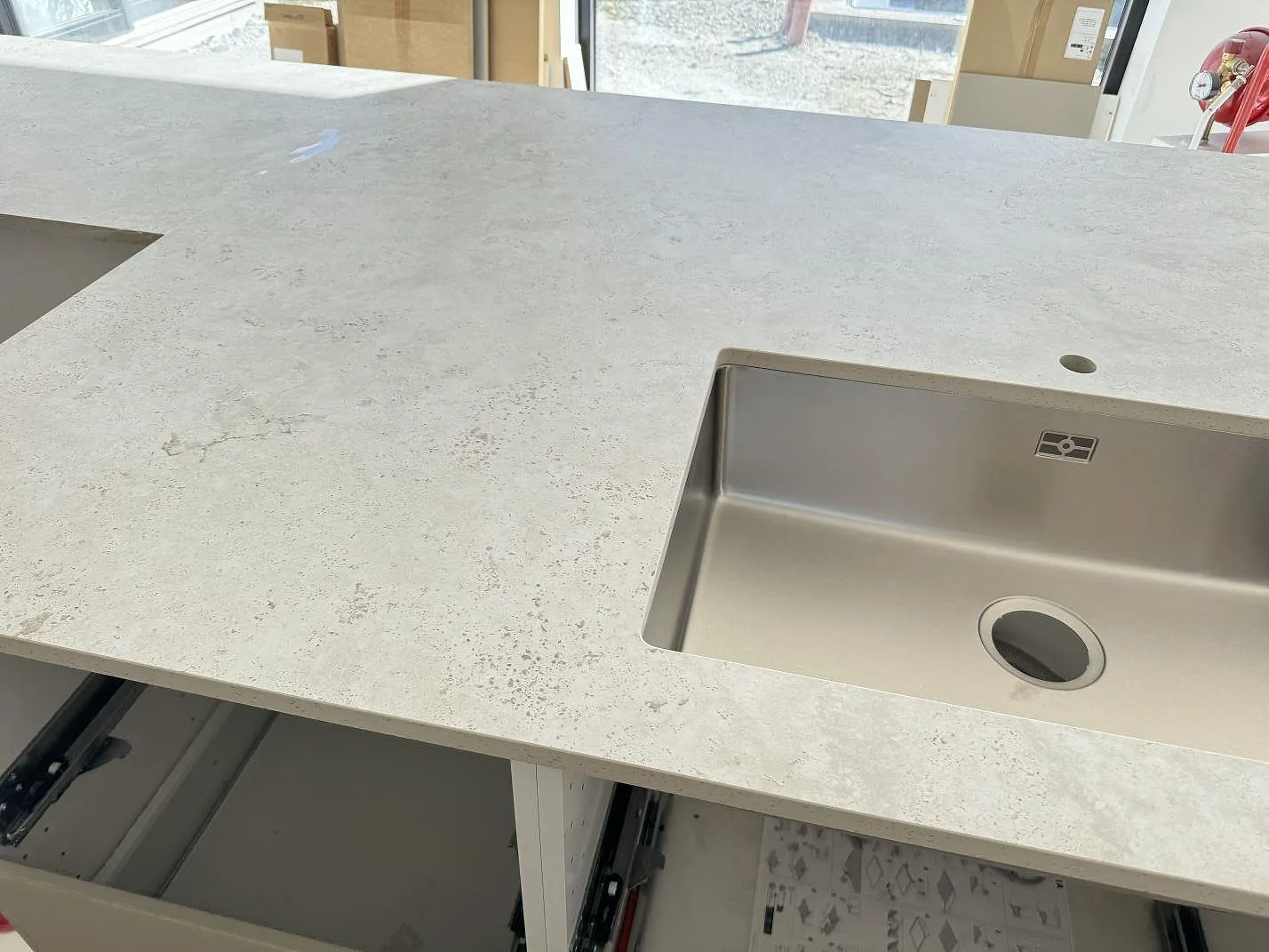 Matt köksbänkskiva i Dekton Tk05 Sabbia med rostfri diskho och synligt blandarhål i ett kök i Oxie.