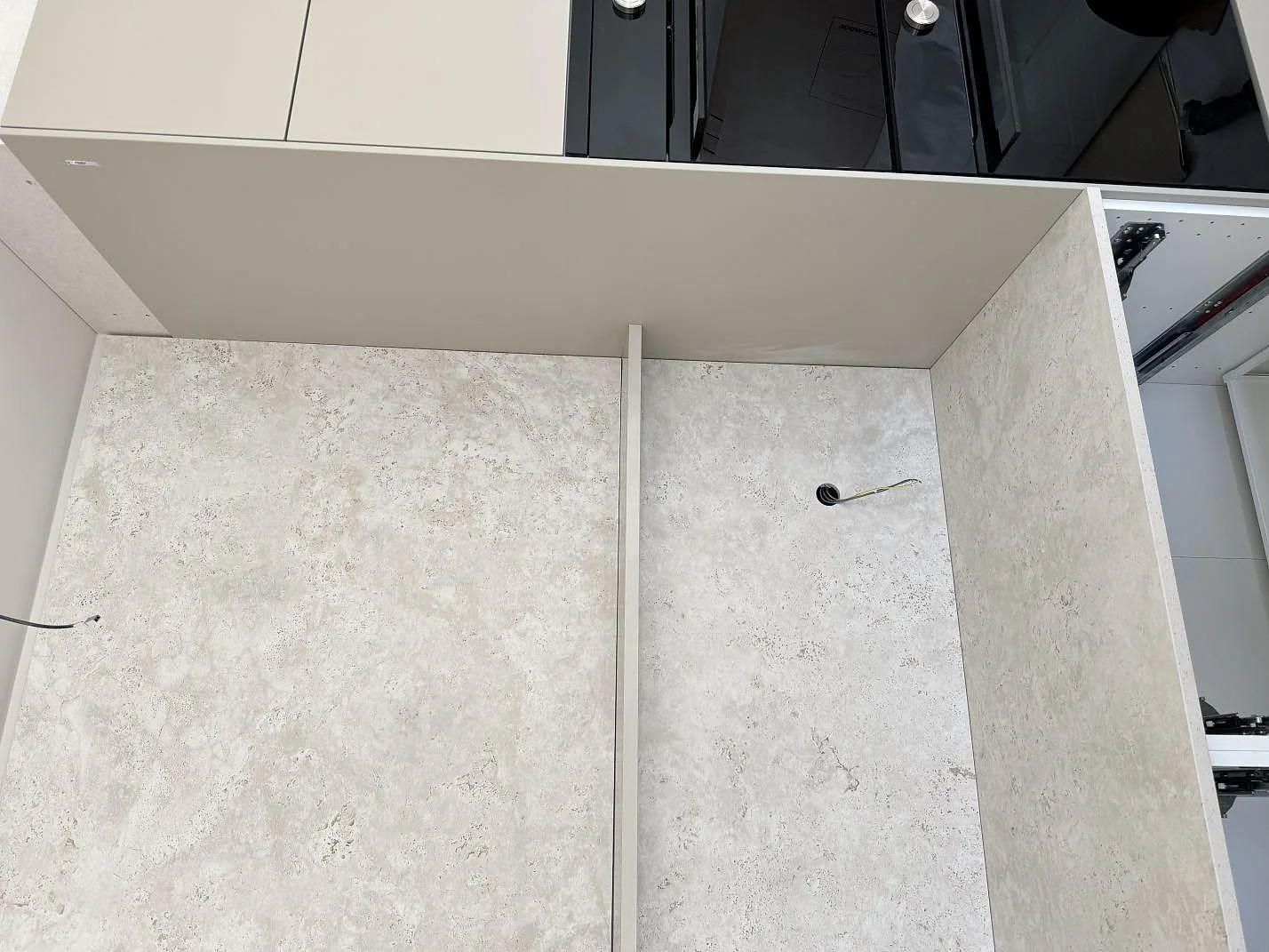 Köksbänkskiva och hög väggbeklädnad i matt Dekton Tk05 Sabbia med häll och öppna stommar i Oxie.