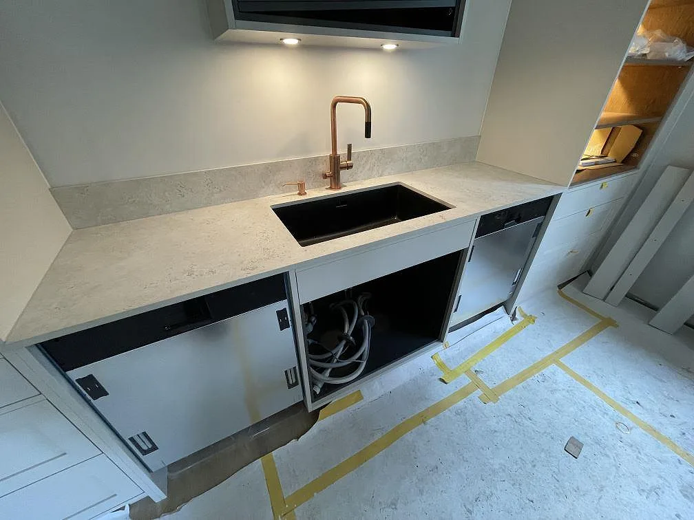 Bänkrad i matt Dekton Tk05 Sabbia med låg stänkkant, svart diskho och kopparfärgad blandare i Saltsjö Duvnäs.