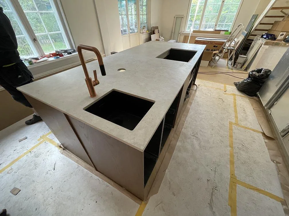 Köksö i matt Dekton Tk05 Sabbia med svart diskho, hällöppning och ljus keramikyta i Saltsjö Duvnäs.