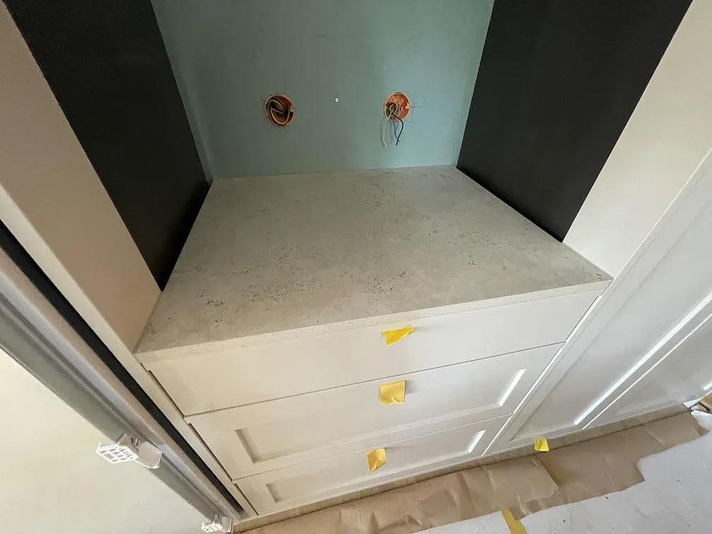 Sidobänk i matt Dekton Tk05 Sabbia med ljus sandgrå keramikyta i nisch med vita luckor i Saltsjö Duvnäs.