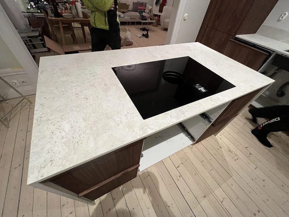 Köksö i matt Dekton TK05 Sabbia med svart induktionshäll och ljus keramikyta i ett kök i Stockholm.