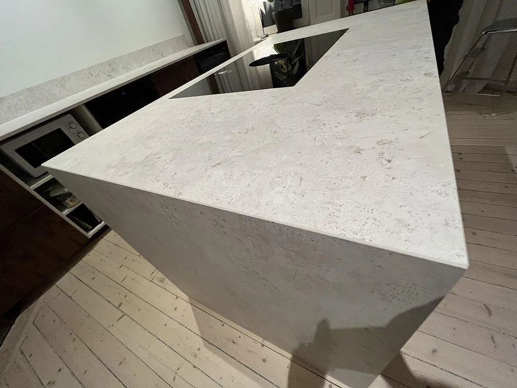 Köksö med vattenfallssida i matt Dekton TK05 Sabbia och sammanhängande ljus keramikyta i Stockholm.