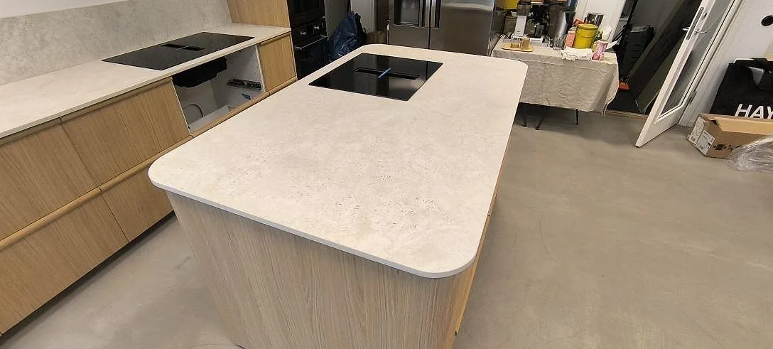Köksö i matt Dekton Tk05 Sabbia keramik med rundade hörn och häll, monterad i ett kök i Stockholm.