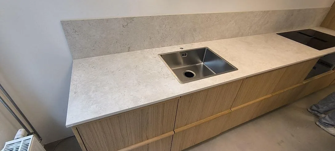 Lång köksbänkskiva i matt Dekton Tk05 Sabbia keramik med rostfri diskho, häll och stänkskydd i Stockholm.