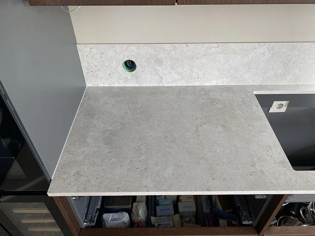 Närbild på matt Dekton Tk05 Sabbia som köksbänkskiva och stänkskydd vid en öppning i ett kök i Väjern.