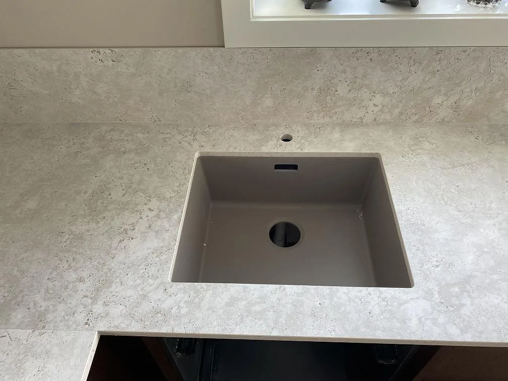 Diskho i köksbänkskiva i matt Dekton Tk05 Sabbia med matchande stänkskydd under fönster i Väjern.