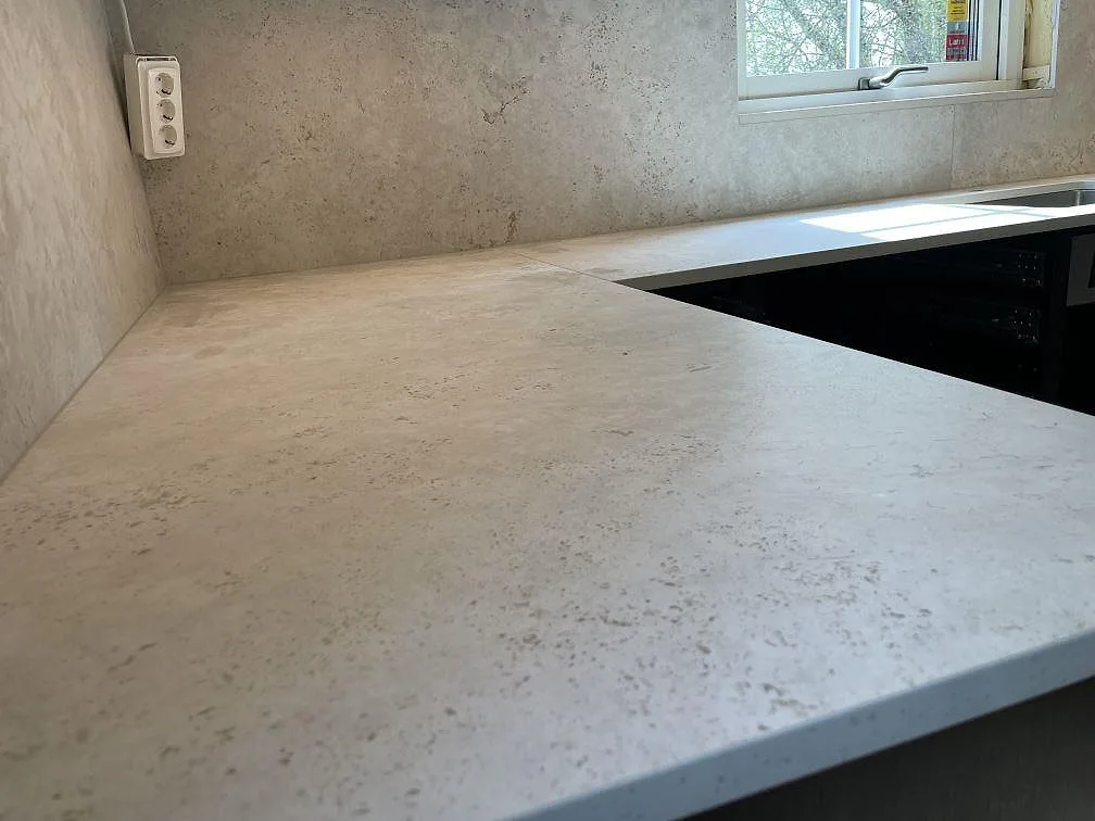 Närbild på matt Dekton Tk05 Sabbia i keramik, med ljus beige yta och stänkskydd i kök i Vaxholm.
