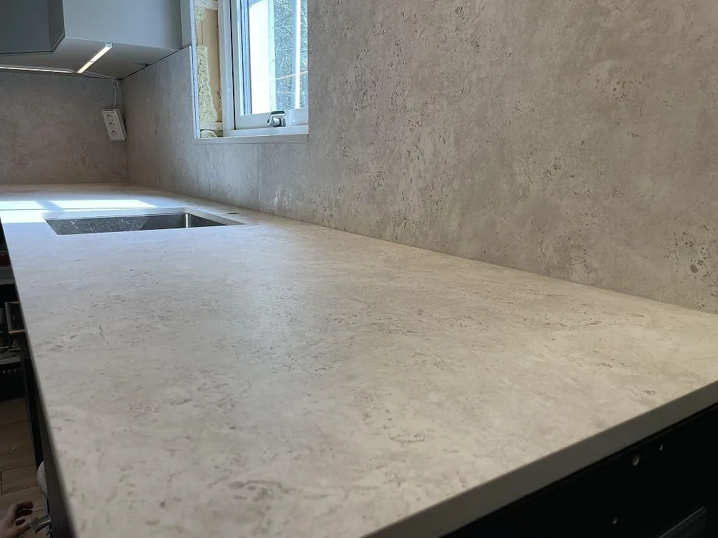 Detaljbild av köksbänkskiva och stänkskydd i matt Dekton Tk05 Sabbia vid diskhozonen i Vaxholm.