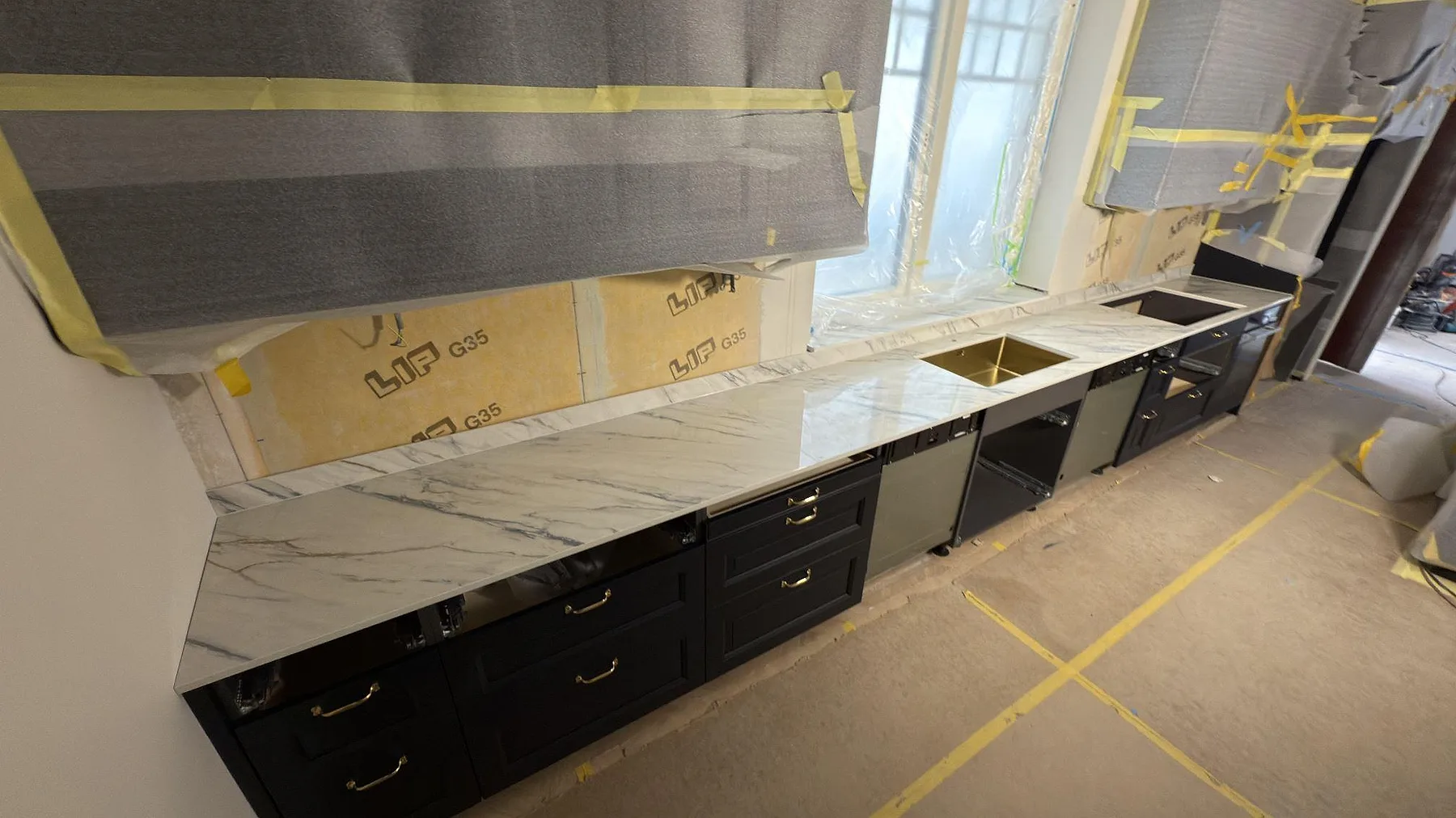 Vinklad vy över polerad Dekton Trance som keramisk bänkskiva med marmorerad ådring och stänkskydd under montering i Åkersberga.