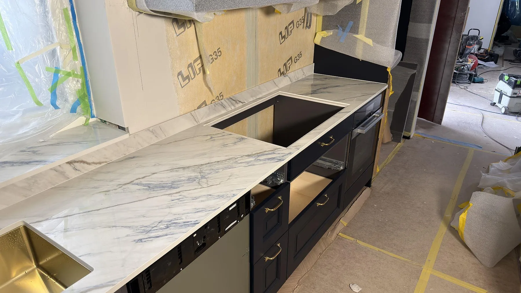 Rak bänkskiva i polerad Dekton Trance keramik med grå ådring, uppvikt stänkskydd och öppna köksstommar i Åkersberga.