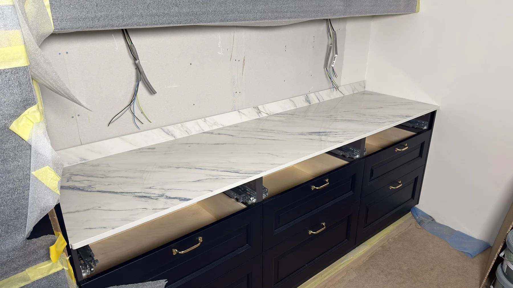 Närbild av polerad Dekton Trance som keramisk köksbänkskiva med låg stänkkant och synliga eldragningar under montering i Åkersberga.