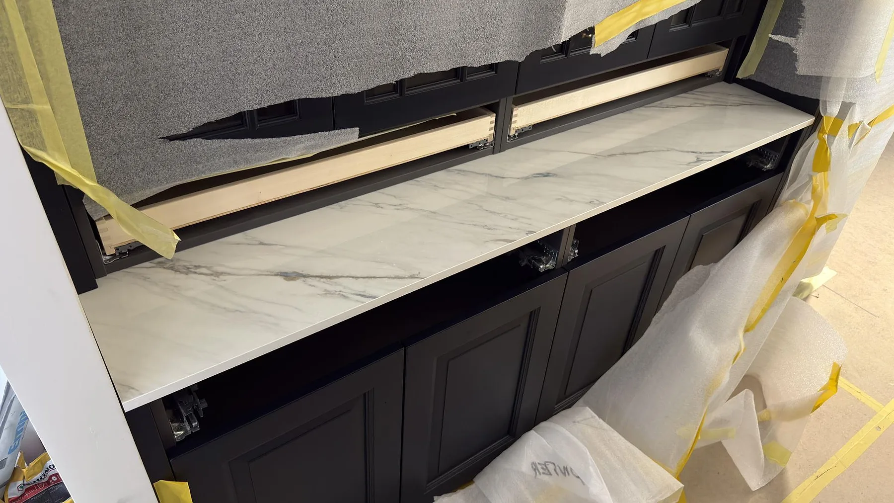 Detalj av polerad Dekton Trance bänkskiva i keramik med vit botten, grå ådring och mörka köksskåp i Åkersberga.