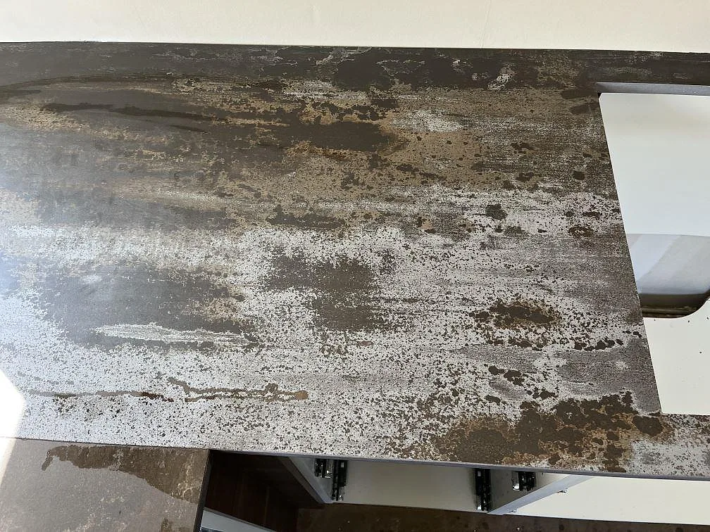 Installerad köksbänkskiva i mörk Dekton Trilium med vita köksstommar under montering i Åstorp.