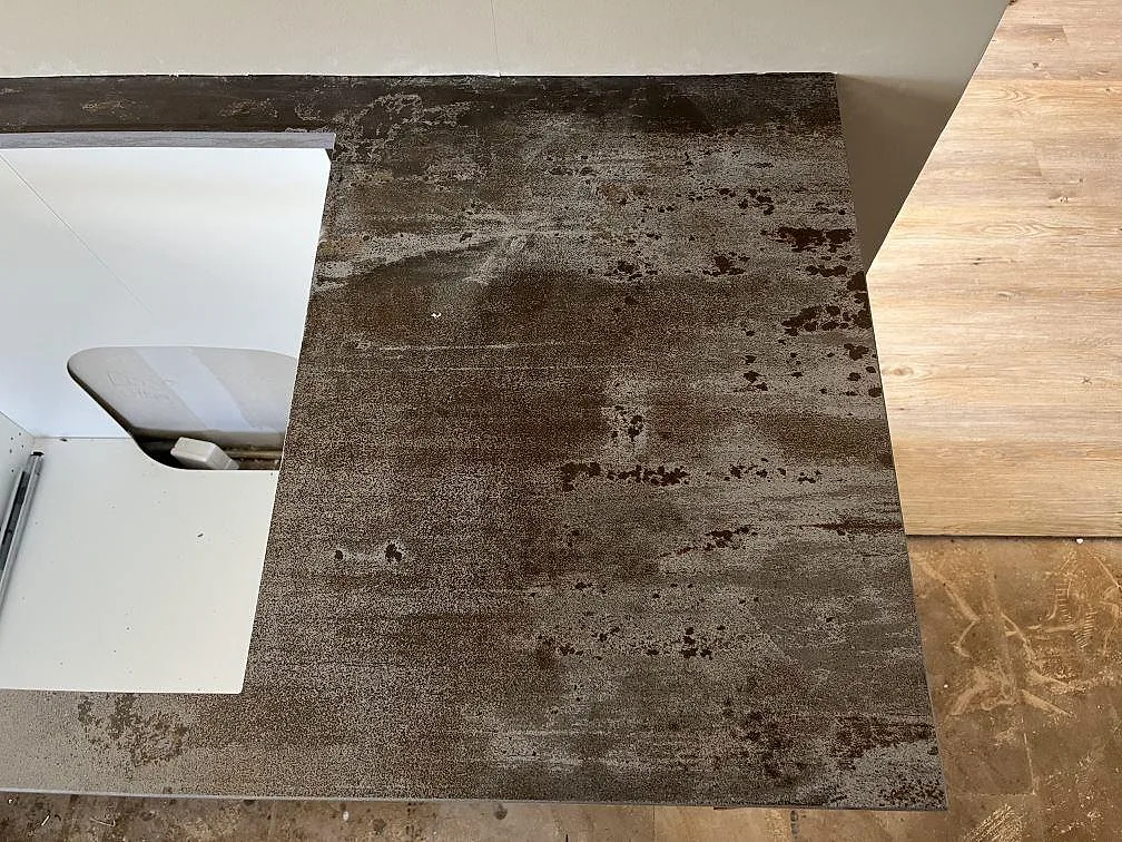 Mörk Dekton Trilium köksbänkskiva sedd uppifrån med rostfri diskho och vit köksstomme i ett kök i Åstorp.