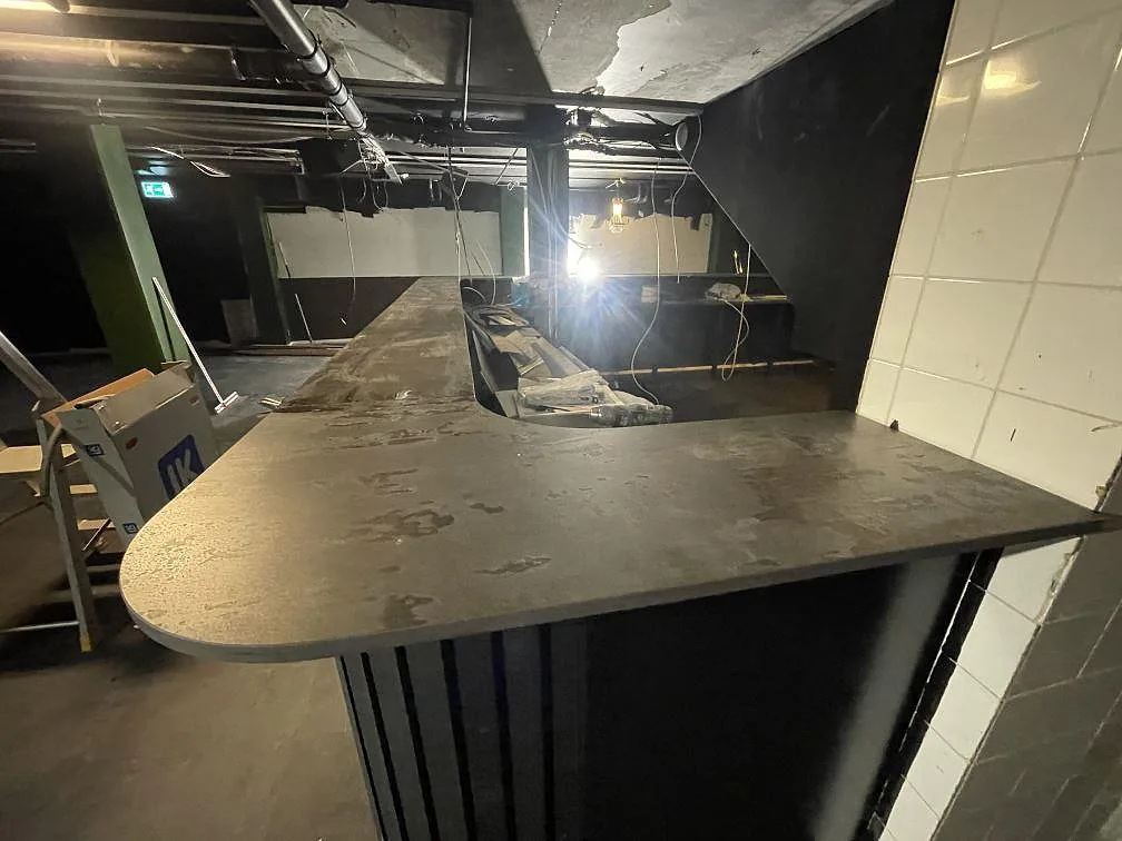 Närbild på bred barände i 20 mm matt Dekton Trilium keramik under montering i en restaurang i Borås.