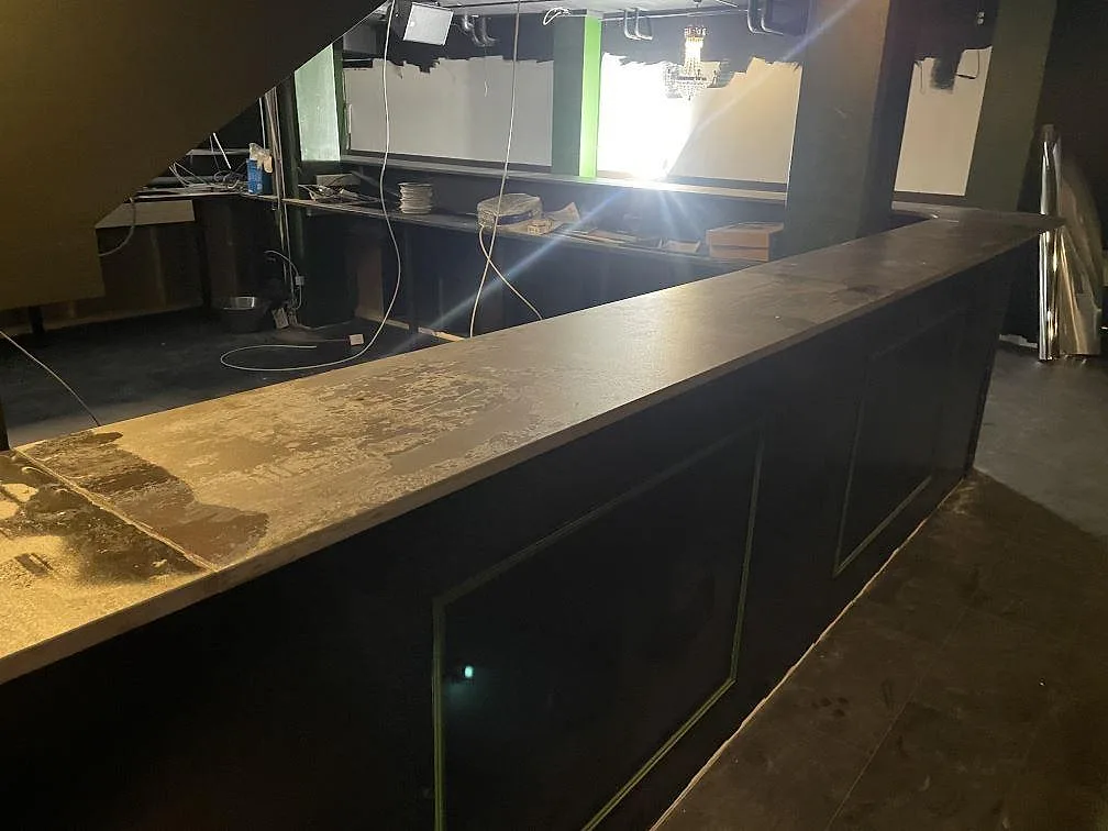Lång serveringsdisk i matt Dekton Trilium keramik med byggbelysning och öppna installationer i Borås.
