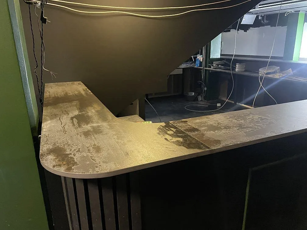 U-formad bardisk i matt Dekton Trilium med rundade hörn vid trappöppning i en restaurangmiljö i Borås.