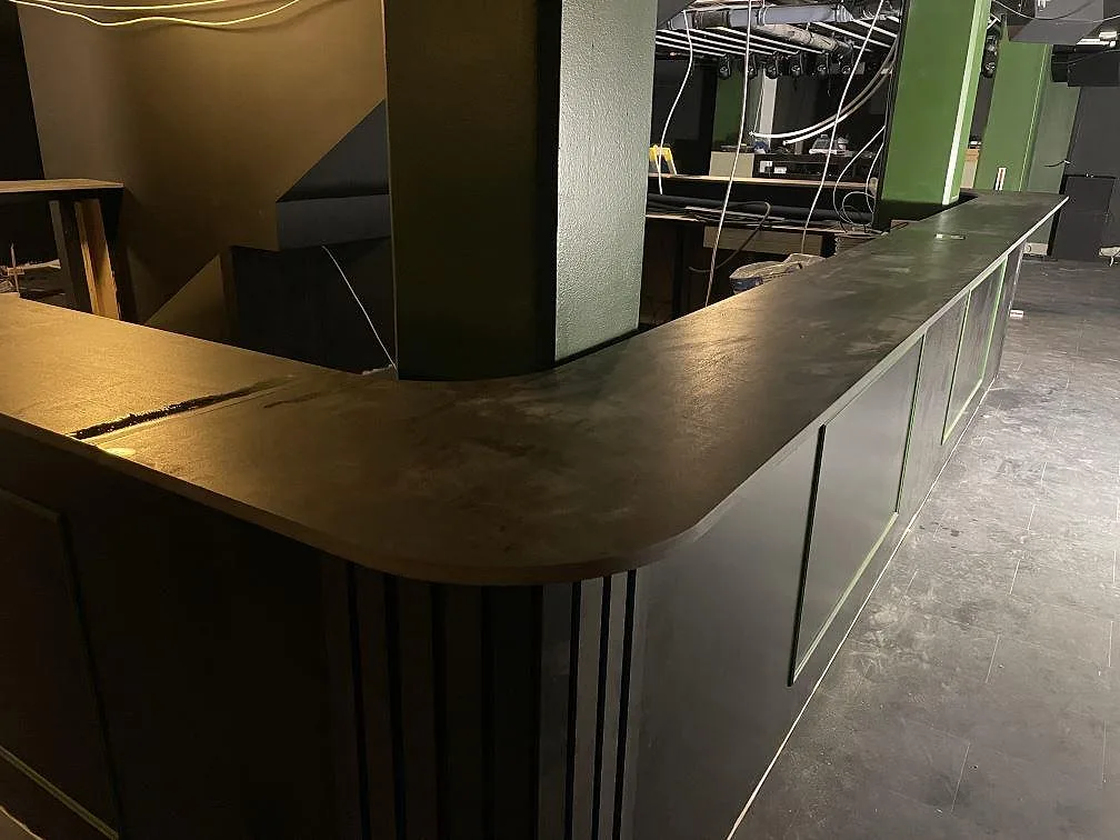 Detalj av rundat hörn på bardisk i matt Dekton Trilium med mörk ådring och bygggolv i Borås.