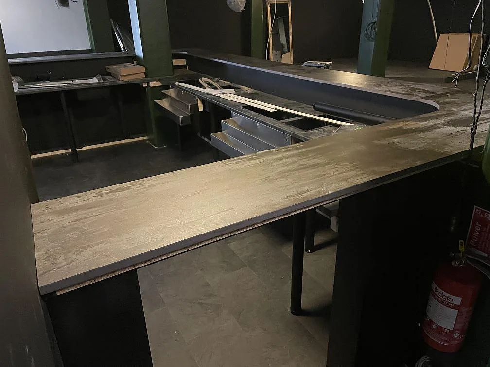 Bardisk i matt Dekton Trilium keramik, 20 mm, med lång U-formad yta i en restaurang under montering i Borås.