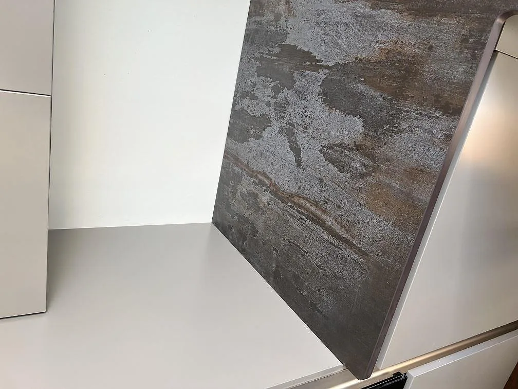 Uppvikt stänkkant i matt Dekton Trilium keramik bakom vit köksinredning i Hasslö.