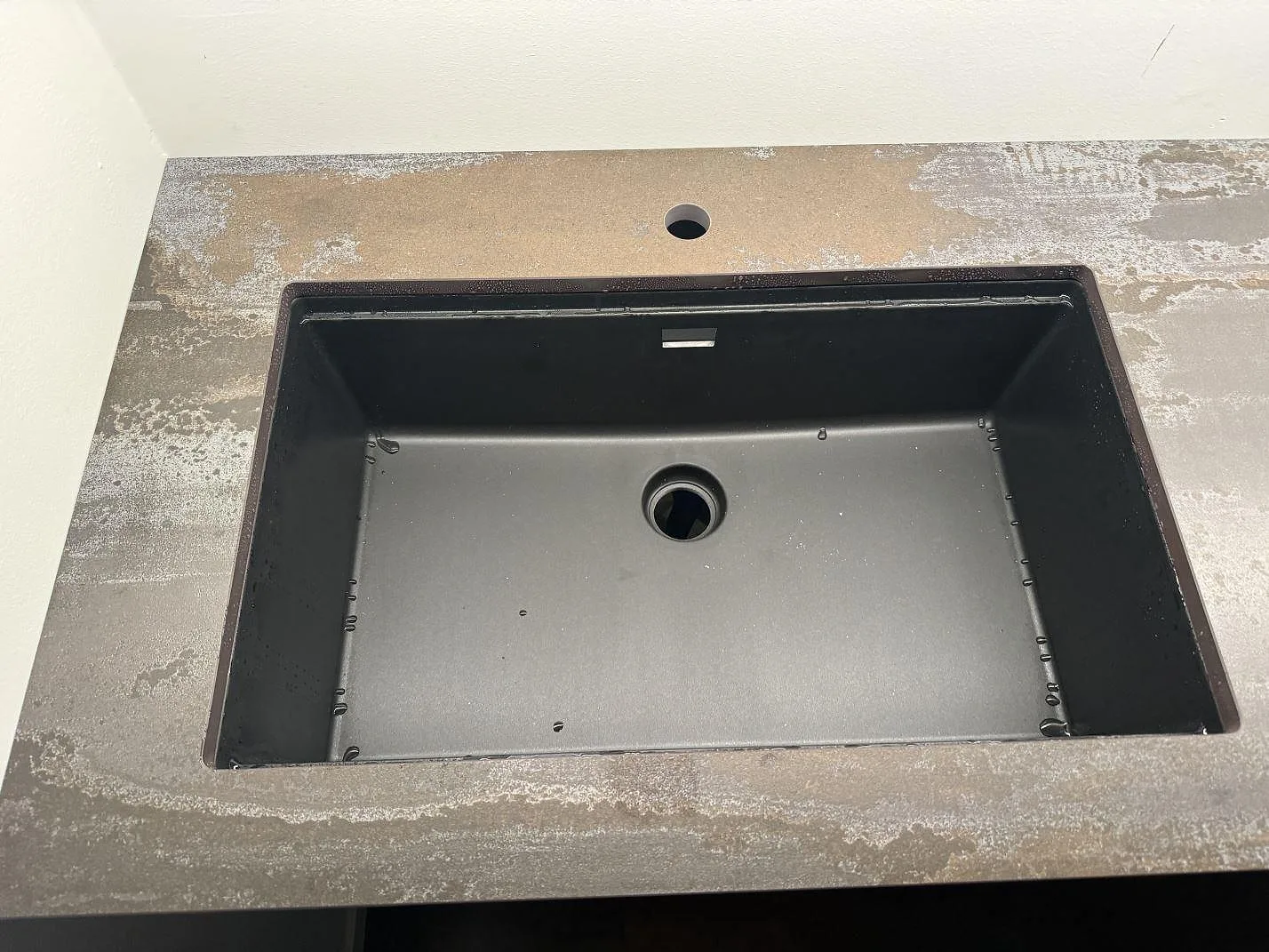 Närbild på svart diskho i matt Dekton Trilium med synlig grå och rostad ådring i Helsingborg.