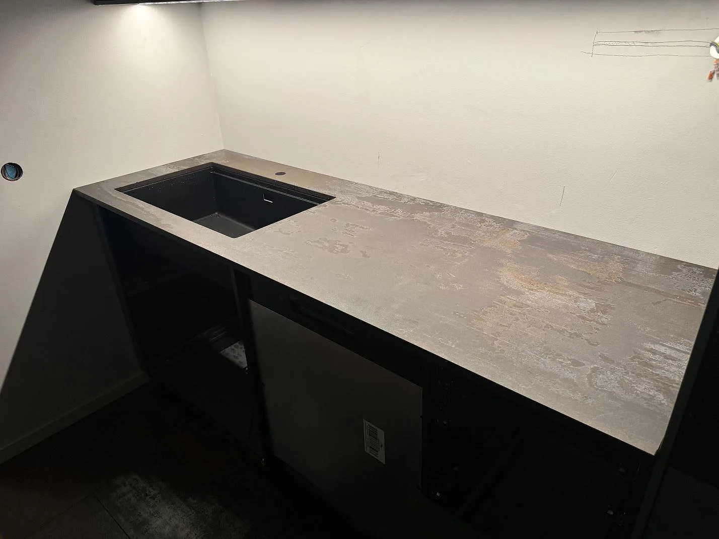 Lång köksbänkskiva i matt Dekton Trilium med svart diskho och gråbrun keramikyta i Helsingborg.