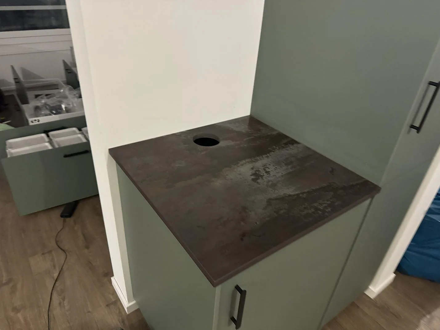 Mindre bänkdel i matt Dekton Trilium med blandarhål på grön stomme i ett kök i Helsingborg.